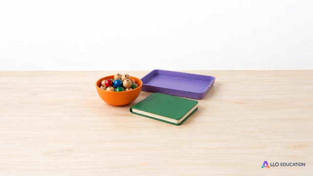 Petit bol orange de perles, plateau violet vide et carnet vert fermé évoquant le calcul de lots et sa vérification.